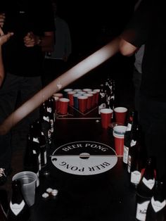 several people are standing around a table with beer cups on it and one person is holding a baseball bat