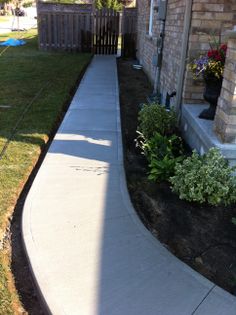 a walkway leading to a house with flowers in the front yard