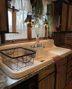 a kitchen sink sitting under a window next to a counter top with a basket on it