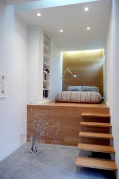 a bed sitting on top of a wooden step next to a window