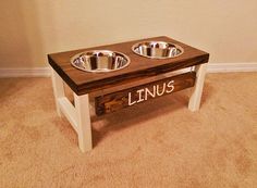 two metal bowls on a wooden table with the word linus painted on it's side