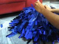 blue tinsel on the floor in front of a red couch with someone's hand reaching for it