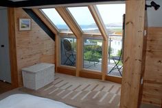 an attic bedroom with wooden walls and windows