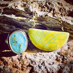 a yellow and blue pendant sitting on top of a rock next to a piece of wood