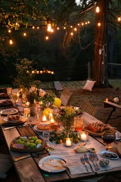 an outdoor dinner table is set with candles and food for the guests to eat at