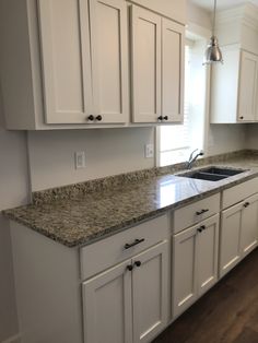 a kitchen with white cabinets and granite counter tops