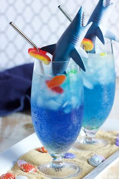 two glasses filled with blue liquid and shark decorations