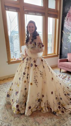 a woman is standing in front of a window wearing a dress with flowers on it