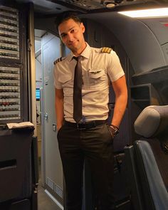 a man in uniform standing next to an airplane control room with controls on the wall