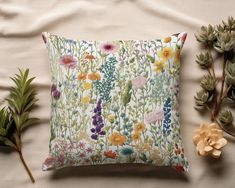 a pillow with colorful flowers on it next to some plants and other things that are laying around