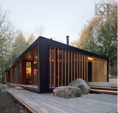 a wooden deck leading up to a small cabin in the woods with rocks and trees surrounding it