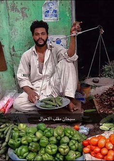 a man sitting on top of a table filled with vegetables