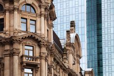 an old building in front of some very tall buildings with windows on the top and bottom