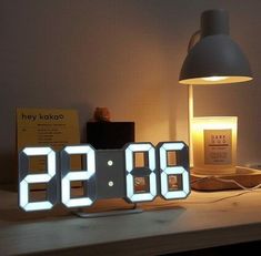 an alarm clock sitting on top of a desk next to a lamp