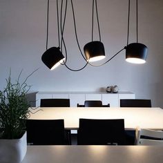 a white table with black chairs and lights hanging from it