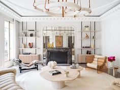 a living room filled with lots of furniture and a chandelier hanging from the ceiling