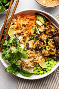 a white bowl filled with salad and chopsticks next to bowls of vegetables, rice and sauce