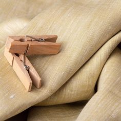 a pair of wooden clothes pins sitting on top of a beige fabric