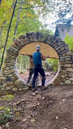 two men working on a stone arch in the woods