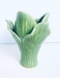 a green vase sitting on top of a white table