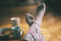 a person's legs with socks and cups on a table