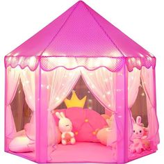 a pink play tent with white curtains and lights on it's sides, filled with stuffed animals