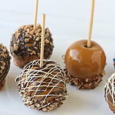 six chocolate covered donuts with caramel and sprinkles on sticks in front of them