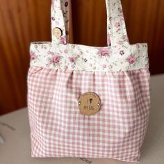 a pink and white checkered bag with a wooden button on the front, sitting on a table