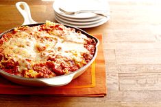 a casserole dish with meat and cheese in it on a napkin next to plates