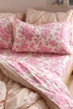 a bed covered in pink and white sheets with pillows on top of the bedspread