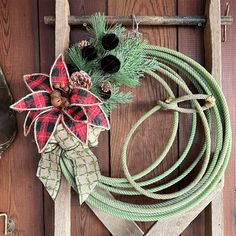 a christmas wreath with pine cones and other decorations on top of a wooden crate next to a pair of scissors