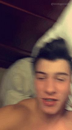 a blurry image of a shirtless man in bed with his head turned to the side