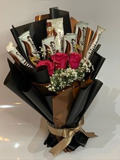 a bouquet of roses and chocolate bars wrapped in black paper