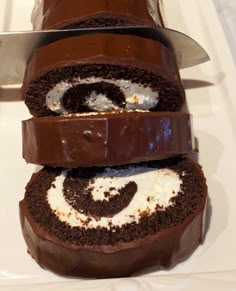 there is a chocolate roll with cream filling on the top and one has a knife in it