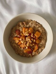 oatmeal with fruit and nuts in a bowl on a white tablecloth