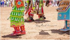 colorfully dressed people standing in the dirt with their feet on each other's legs