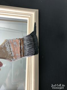 a person holding a paint brush over a window