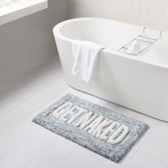 a bath tub sitting next to a bathroom rug