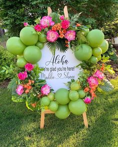 a sign that is on the grass with flowers and fruit around it in front of some trees