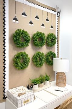 a white desk topped with a lamp and a green wreath on top of a wall