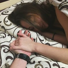 a woman laying in bed with her hands on the pillow