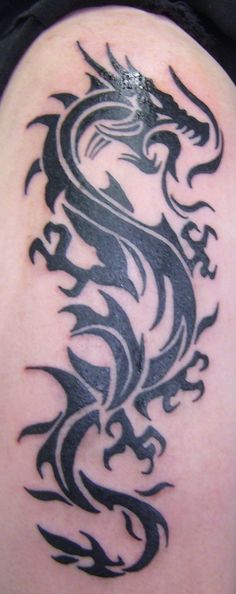 a black and white dragon tattoo on the back of a woman's shoulder,