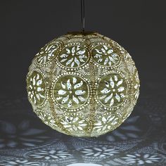 an intricately designed light fixture hanging from a ceiling in front of a dark background