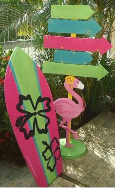 a pink and green surfboard sitting next to a palm tree