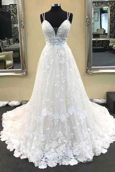 a white wedding dress is on display in front of a mirror with a black mannequin