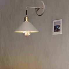 a white lamp hanging from the side of a wall next to a bed with pillows on it