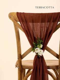 a wooden chair with a red cloth draped over it and flowers on the seat back