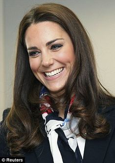 the smiling woman is wearing a black suit and white shirt with red flowers on her neck