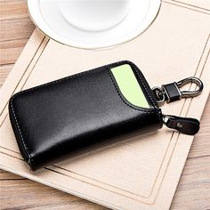 a black leather wallet sitting on top of a table next to a cup and saucer