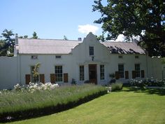 a large white house sitting next to a lush green field